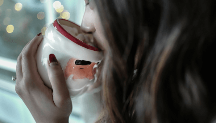 Lady drinking hot chocolate from a Santa mug